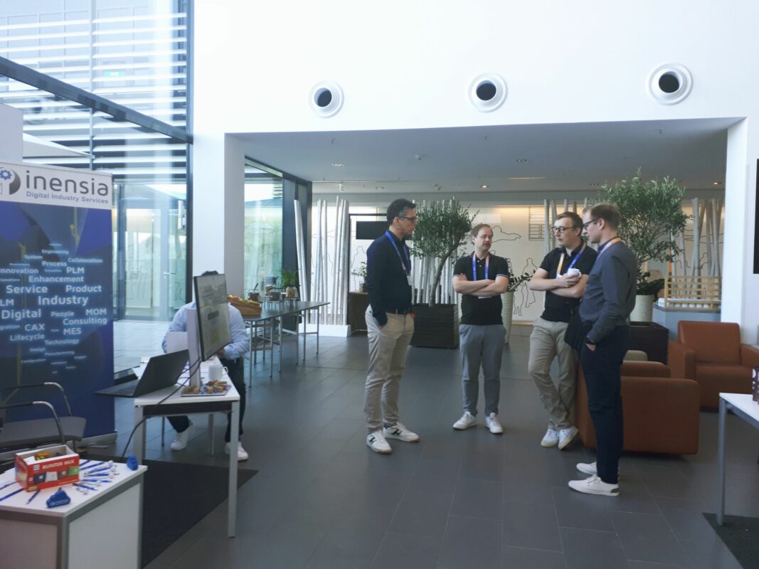Team members engaged in animated conversation with visitors, networking and exchanging ideas at the Siemens PLM Connection 2025 event.